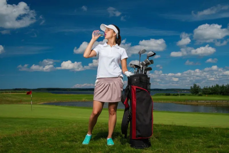 A golfer drinking water on the course